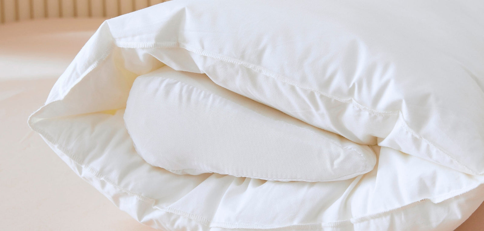 Gros plan sur le cœur d'un oreiller en mousse à mémoire de forme blanc, partiellement sorti de sa housse de protection moelleuse.